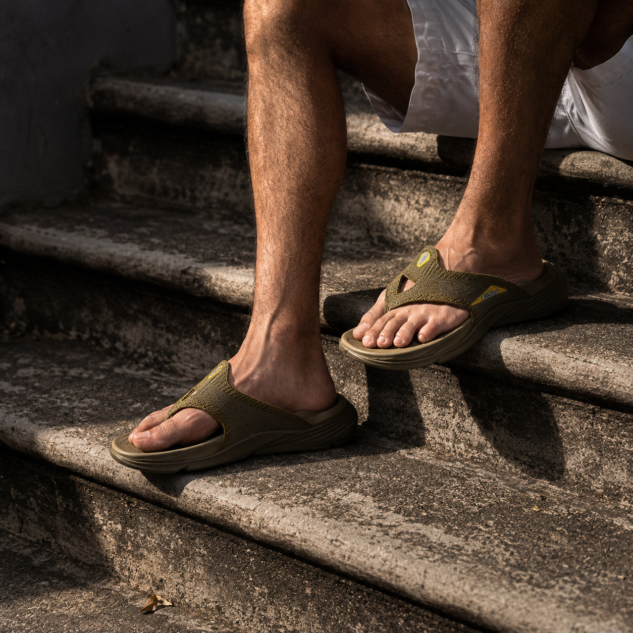 Person wearing army green sandals on a set of stone steps.