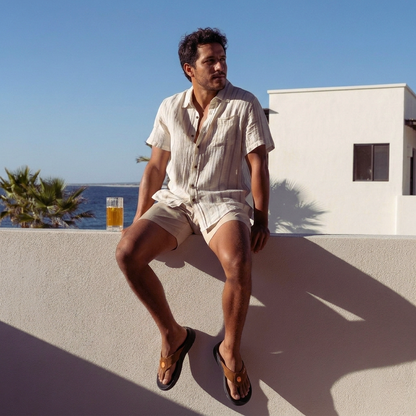A man wearing PCSsole Mocha Suede arch support flip flops sits on the wall
