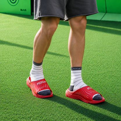 Person wearing red slides with white socks on a green surface