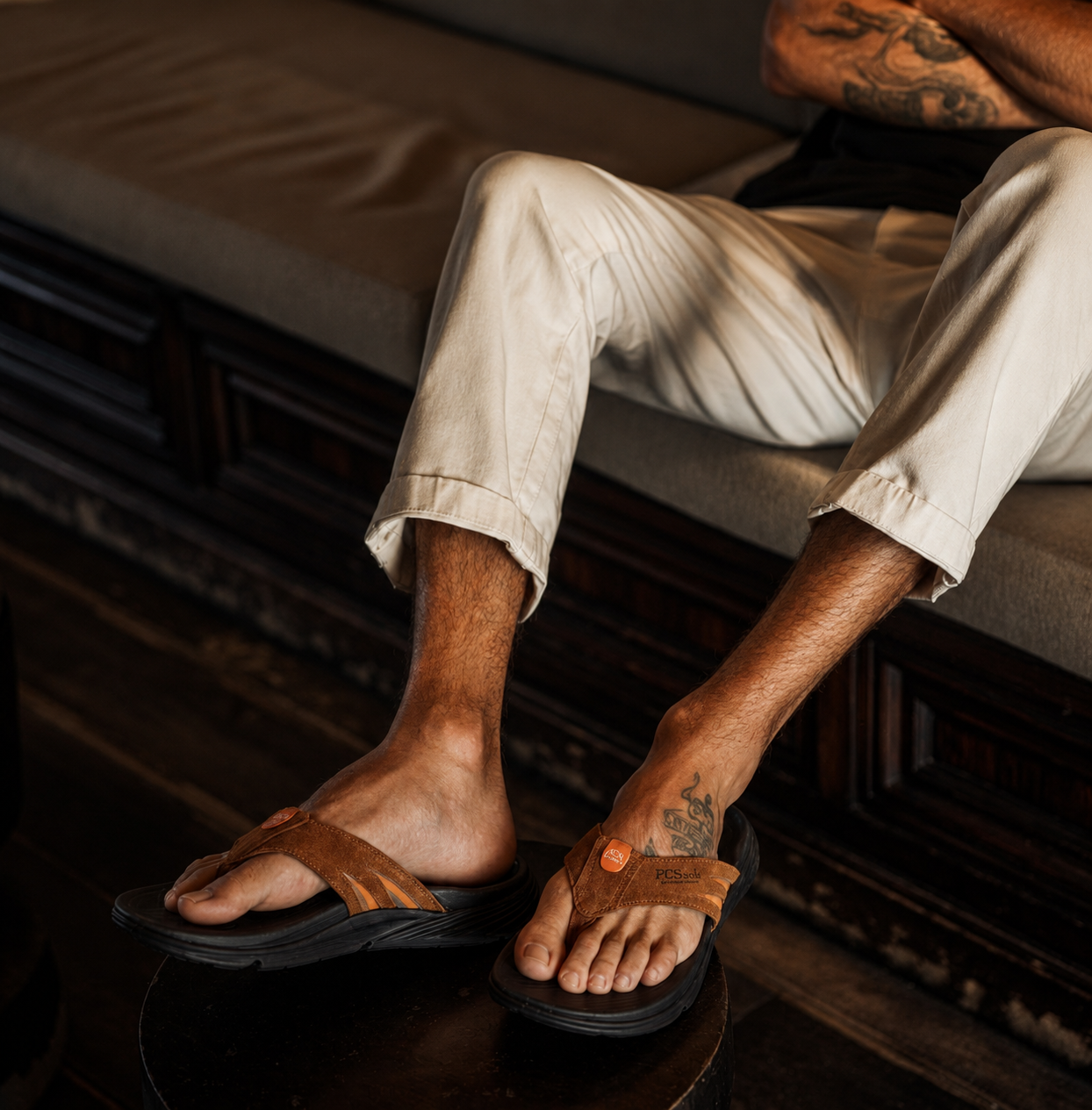 Person wearing suede sandals with a dark background